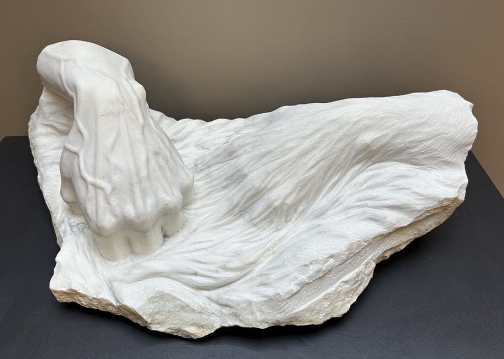 Marble sculpture of two hands, appearing as if intermixed with a water-like material. One hand entering the water, one slightly beneath. Title: “Allora e Ora” (Then and Now) by Elena Mutinelli
