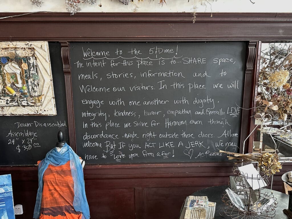 A chalkboard sign in a restaurant reminding be to treat one another with kindness. "But if you act like a jerk", it reads, "we may have to love you from afar".