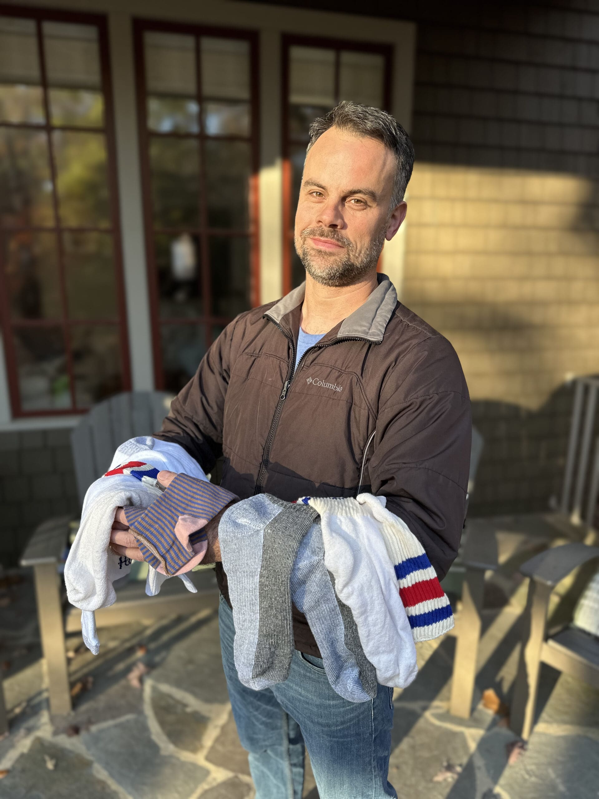 A man holding a bunch of socks draped over his arms.