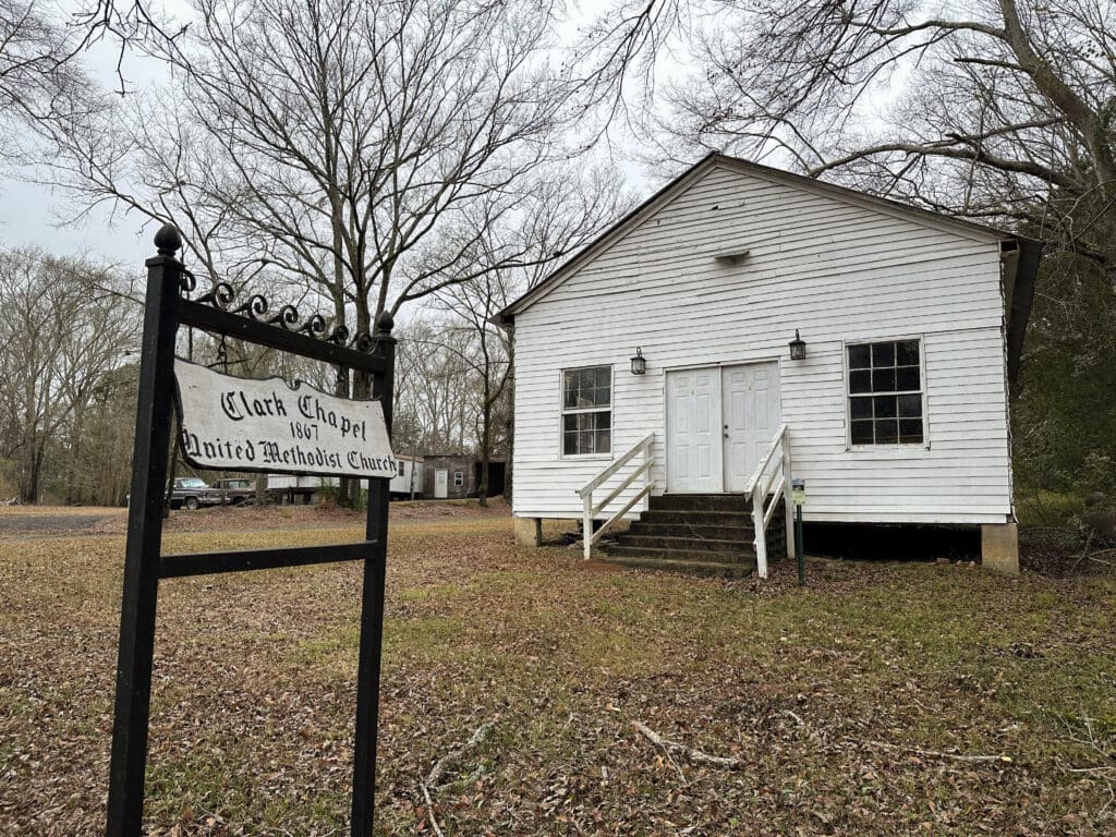 Historic white church building with a sign in front reading "Clark Chapel United Methodist Church, 1867".