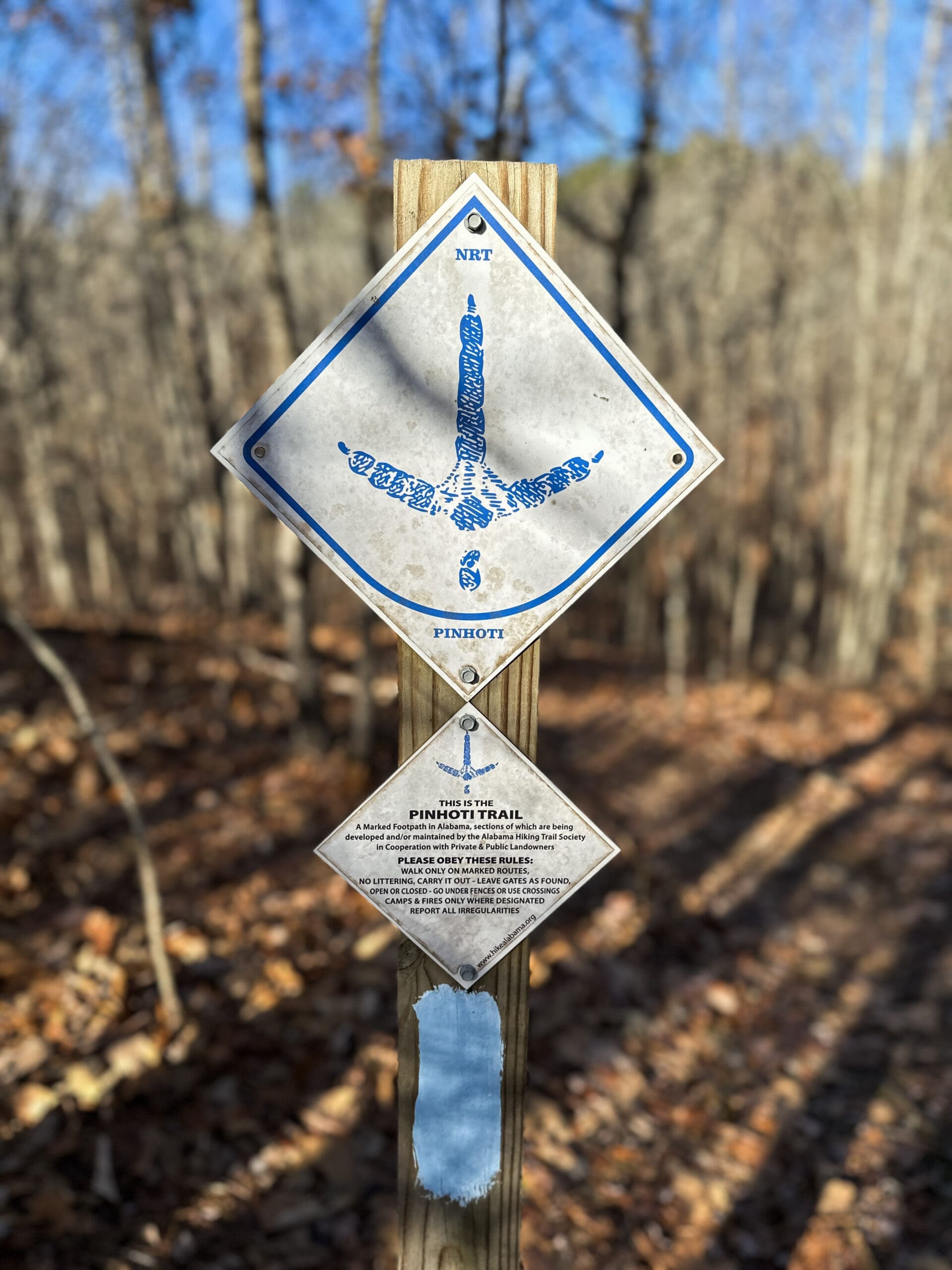 A trail sign with a symbol for a turkey foot. Below the turkey foot, a smaller sign reads "This is the Pinhoti Trail" and includes various trail information.