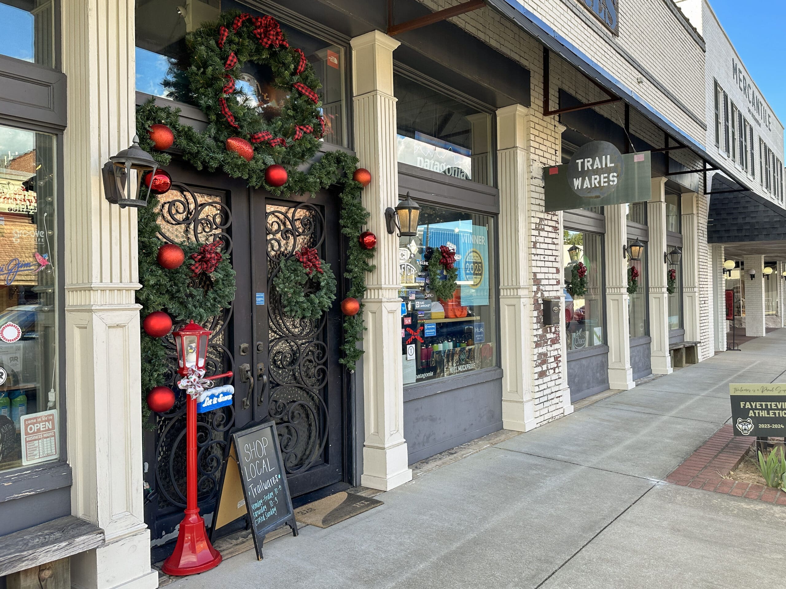 A storefront decorated for Christmas with a wreath and garland. The sign reads "Trailwares".