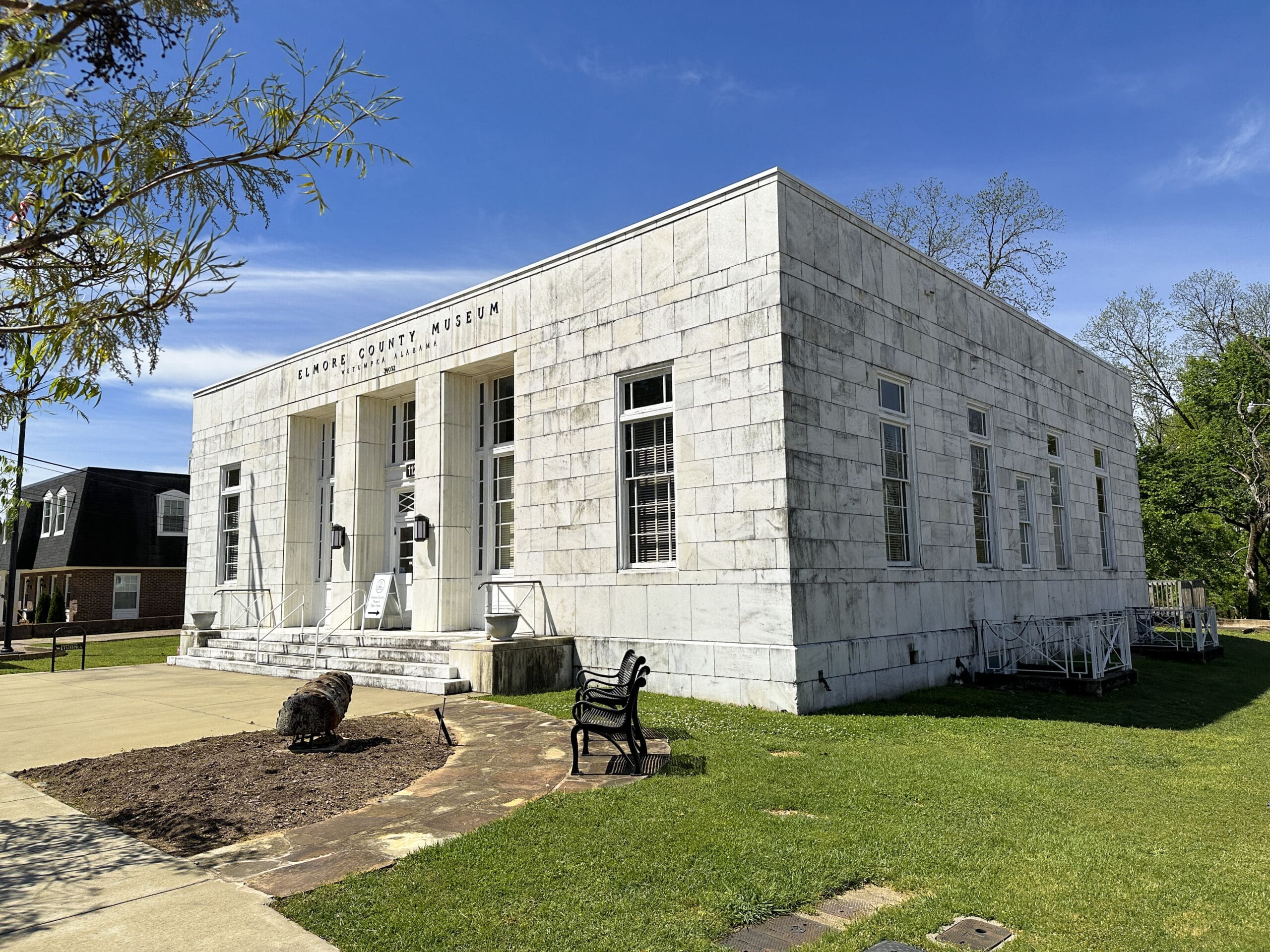 A square, marble building with the words "Elmore County Museum" at top. A two-foot sculpture of a snail sits in front.