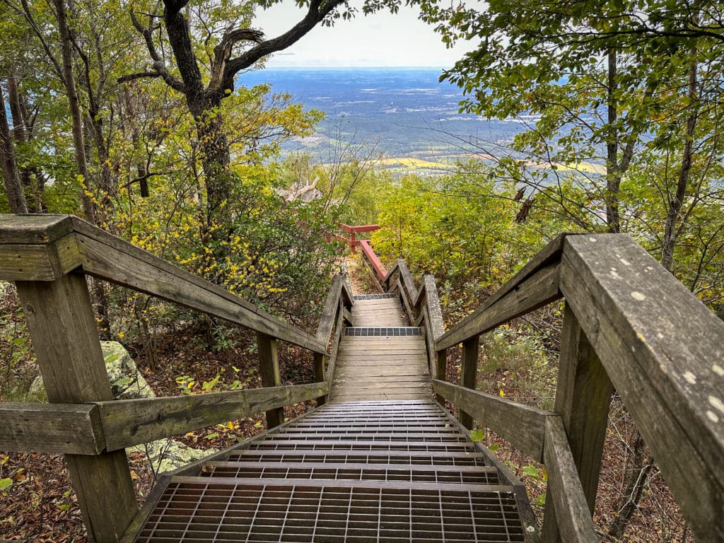 Looking down a large set of stairs, a view from atop a mountain is visible at the bottom.